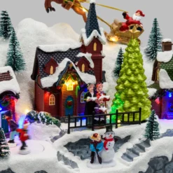 Paesaggio natalizio con Babbo Natale su slitta volante e pattinatori in movimento, led multicolor
