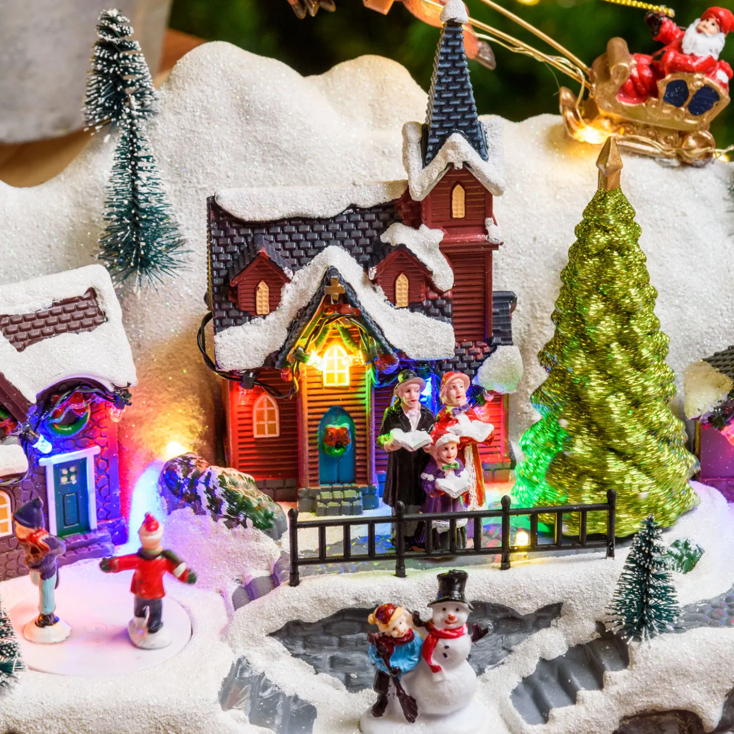 Paesaggio natalizio con Babbo Natale su slitta volante e pattinatori in movimento, led multicolor