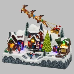 Paesaggio natalizio con Babbo Natale su slitta volante e pattinatori in movimento, led multicolor