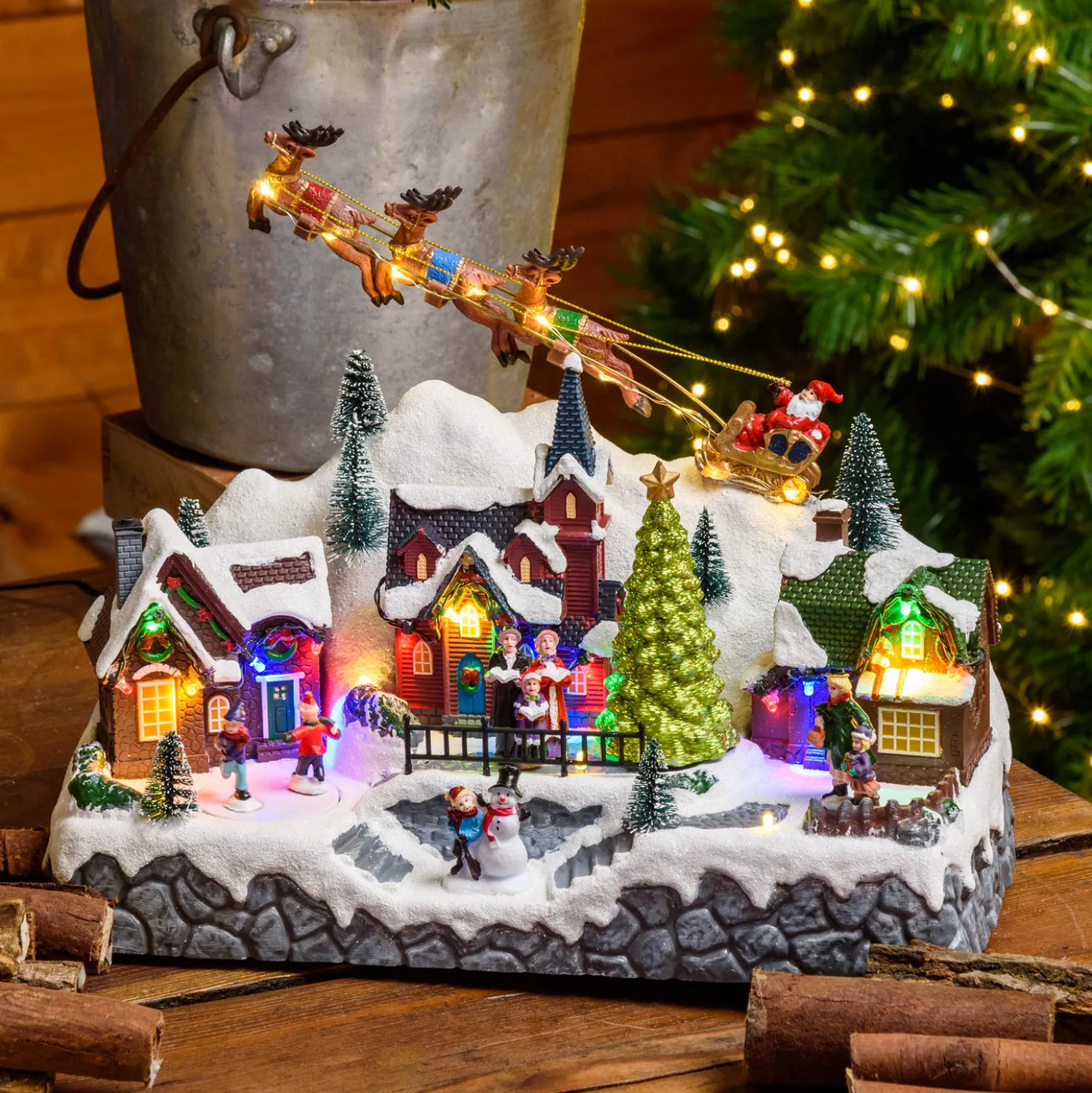 Paesaggio natalizio con Babbo Natale su slitta volante e pattinatori in movimento, led multicolor