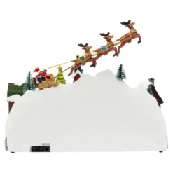 Paesaggio natalizio con Babbo Natale su slitta volante e pattinatori in movimento, led multicolor
