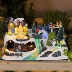 Villaggio di Natale con Paesaggio Innevato, Trenino e Babbo su Slitta rotanti, Ruscello fibre ottiche, h 18 cm, musiche natalizie