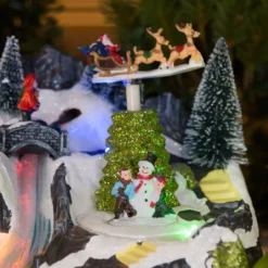 Villaggio di Natale con Paesaggio Innevato, Trenino e Babbo su Slitta rotanti, Ruscello fibre ottiche, h 18 cm, musiche natalizie